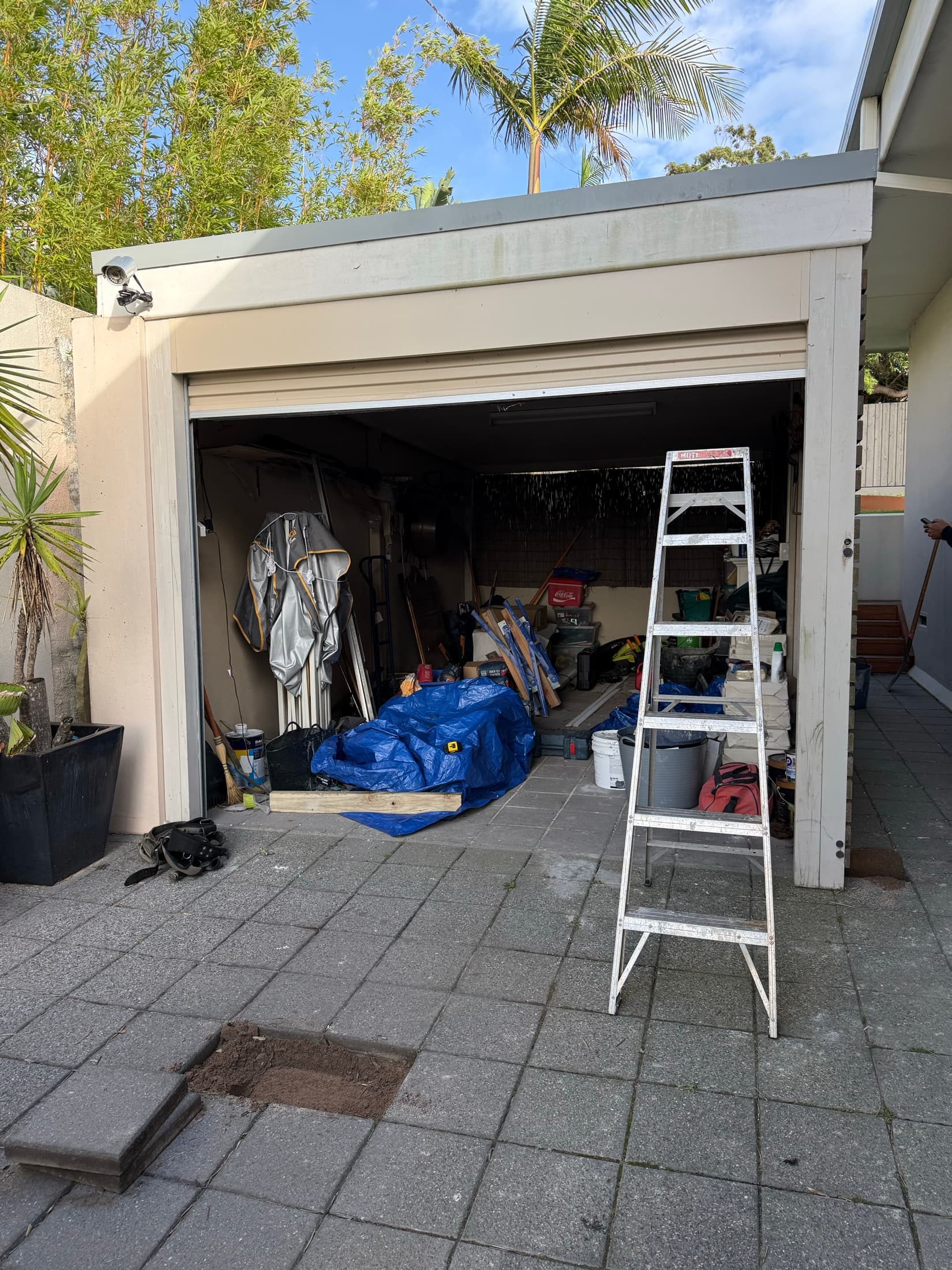 The garage before the works, an open roller door over a cracked concrete apron