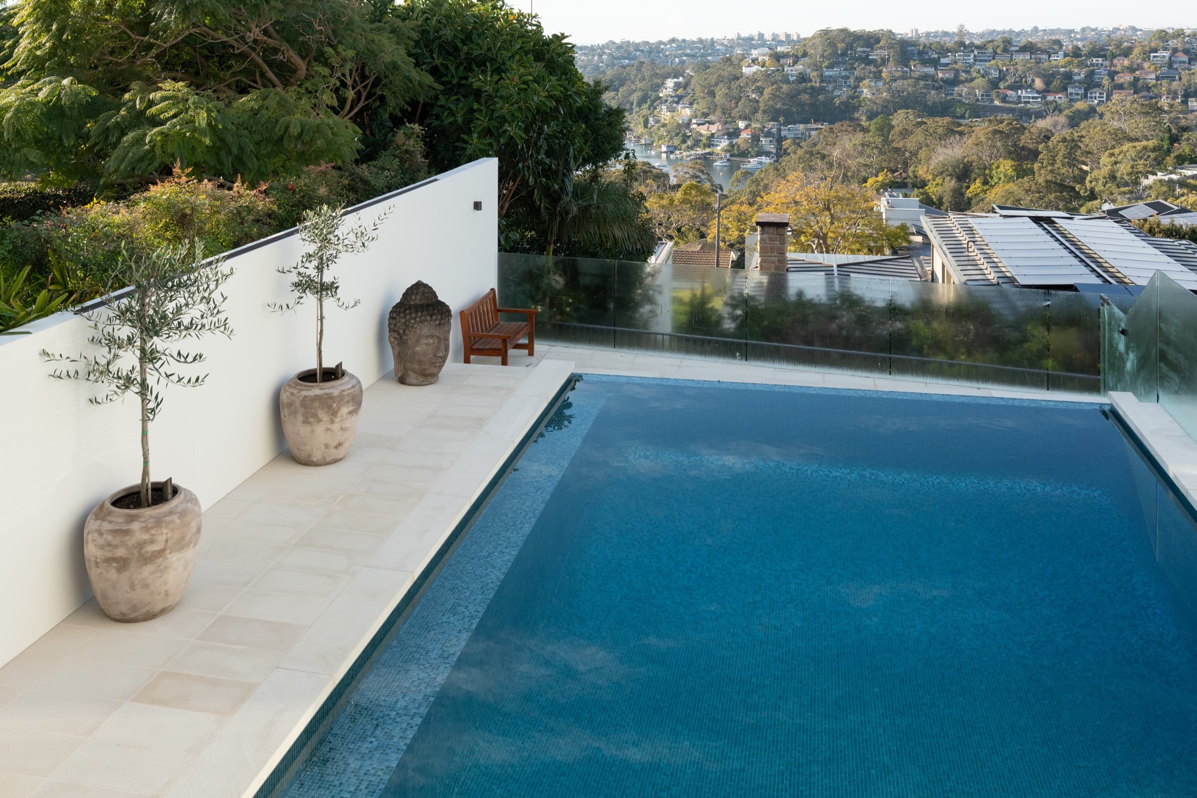 Infinity pool over the harbour, pale stone coping and potted olives on the boundary wall