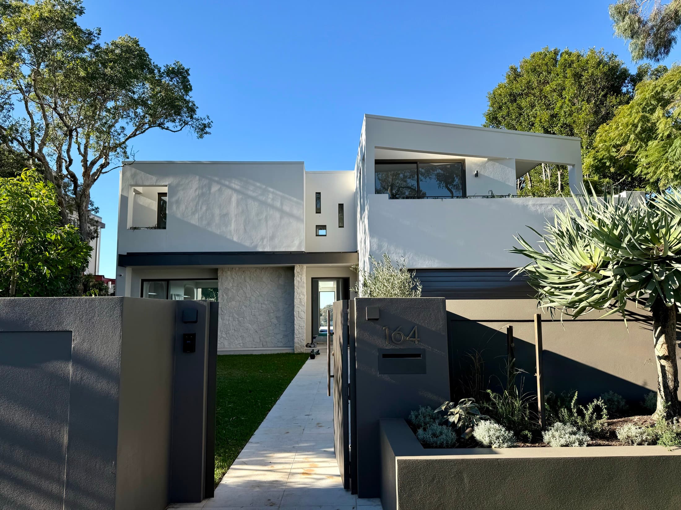 The frontage after the works: rendered walls, a stone entry path and planted beds
